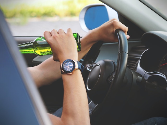 person drinking beer while driving