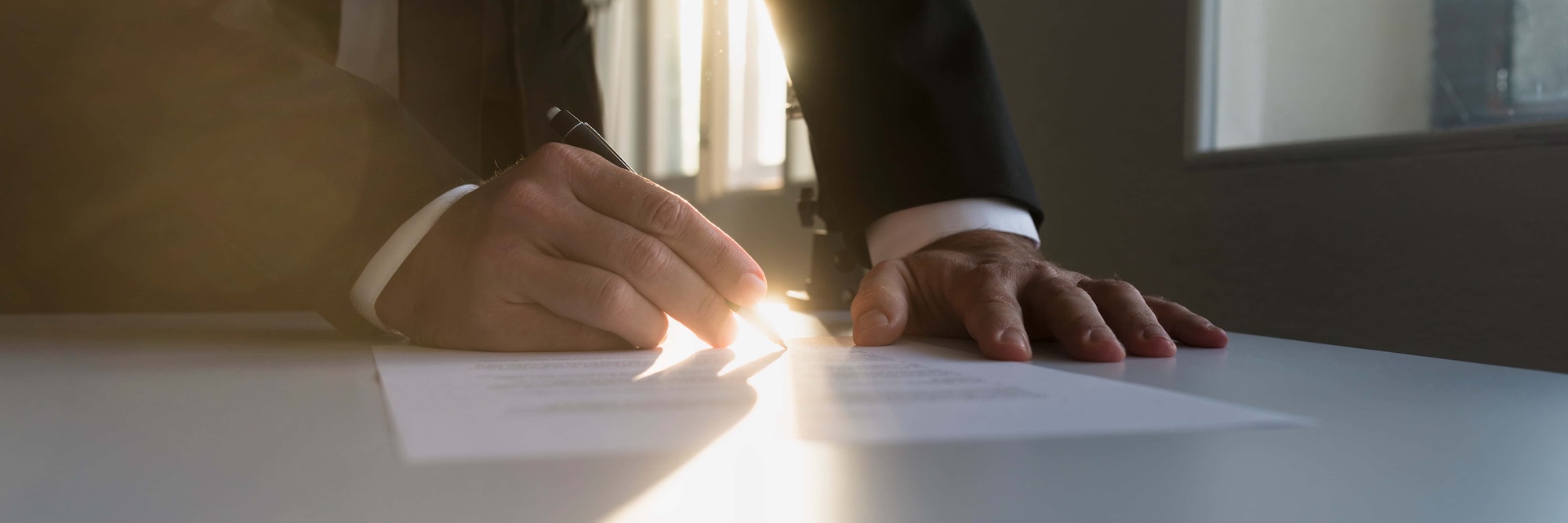 Panorama view of businessman in a shadowy office signing contract