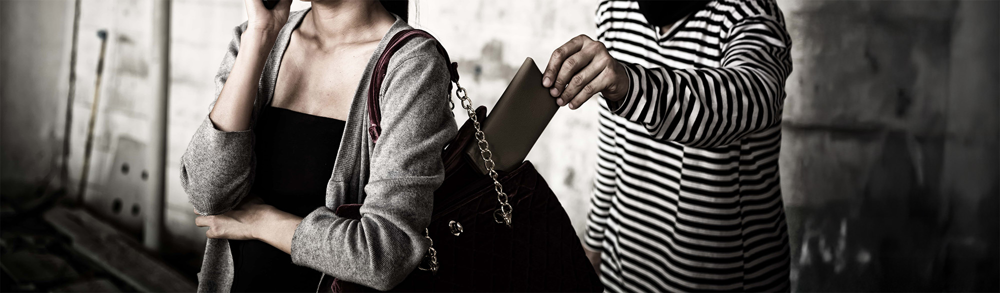 Thief stealing wallet from purse of a woman using mobile phone at the street way. Pickpocket and Security concept