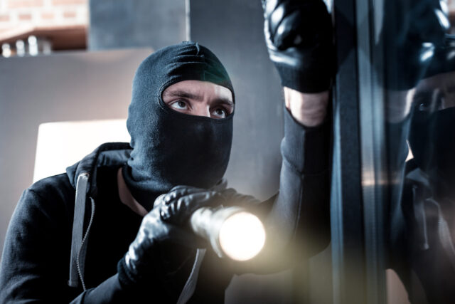 Masked burglar holding a torch