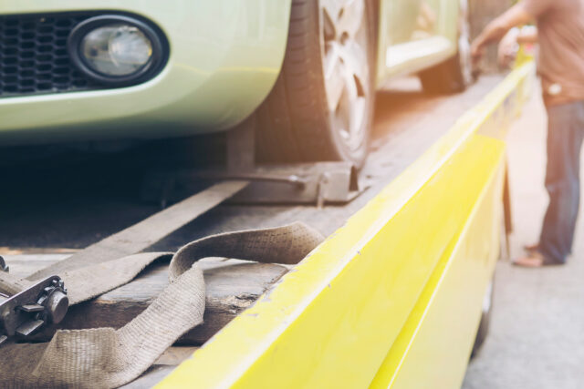 car transporter breakdown lorry during working using locked belt transport other green car for repairing at car center