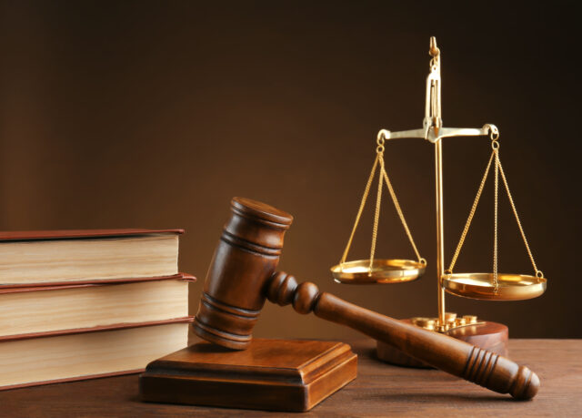 Gavel with books and scales on brown background