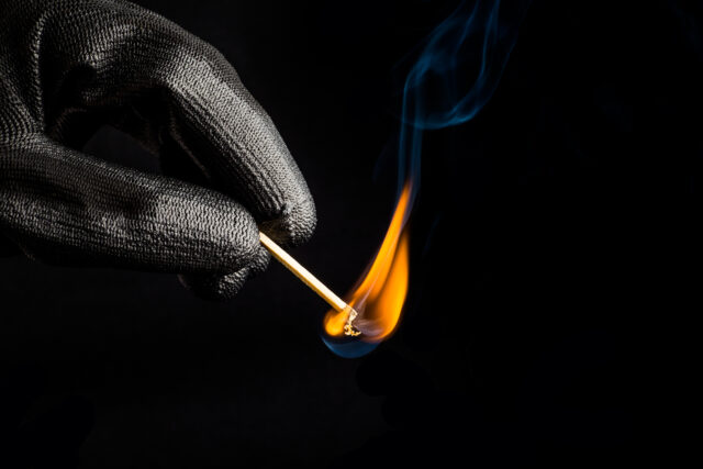 Close-up of hand with match flame