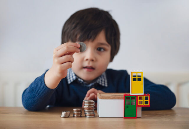 Blurry face of preschool kid showing 10 pence with smiling face.