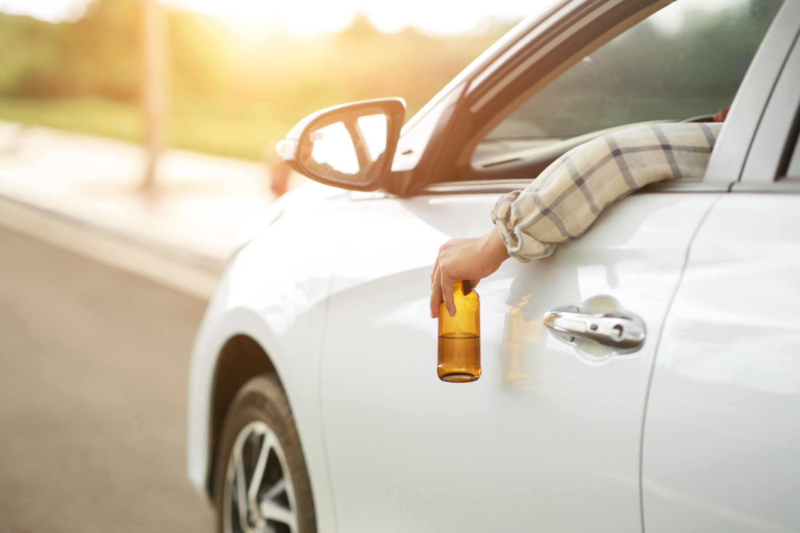 Drunk man holding bottle of beer while driving a car, campaigning for drunken not driving avoiding accidents on road, Don't drink and drive concept.